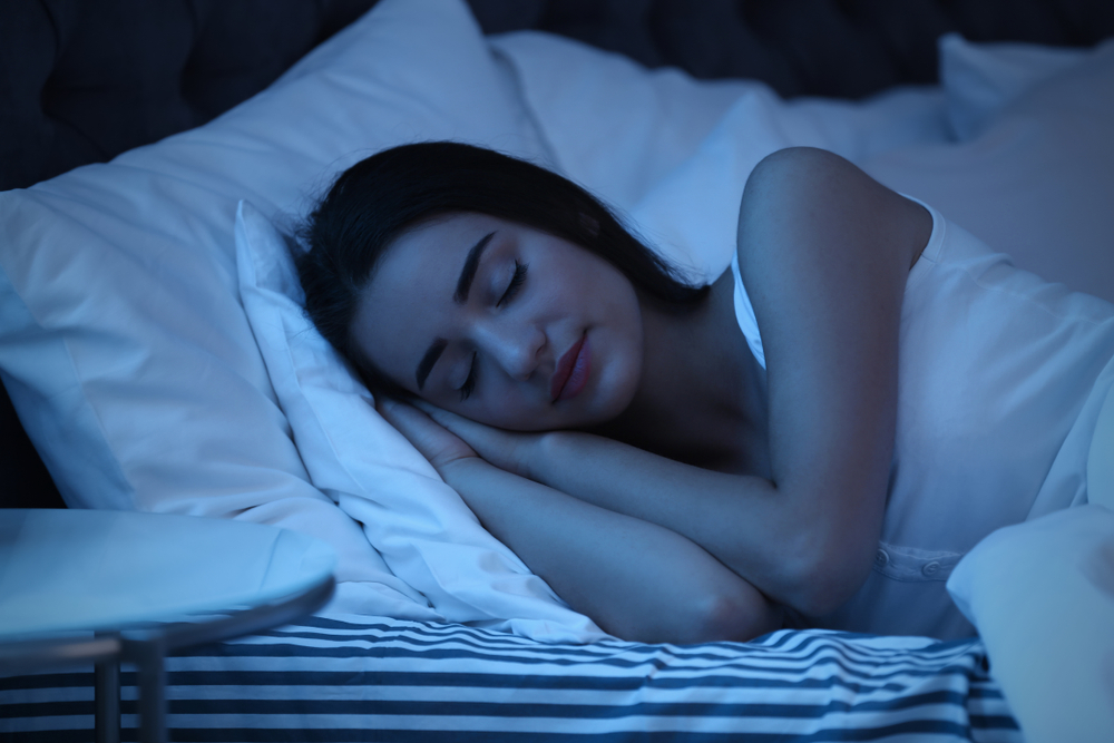 Young woman sleeping peacefully in bed at night during deep restorative sleep